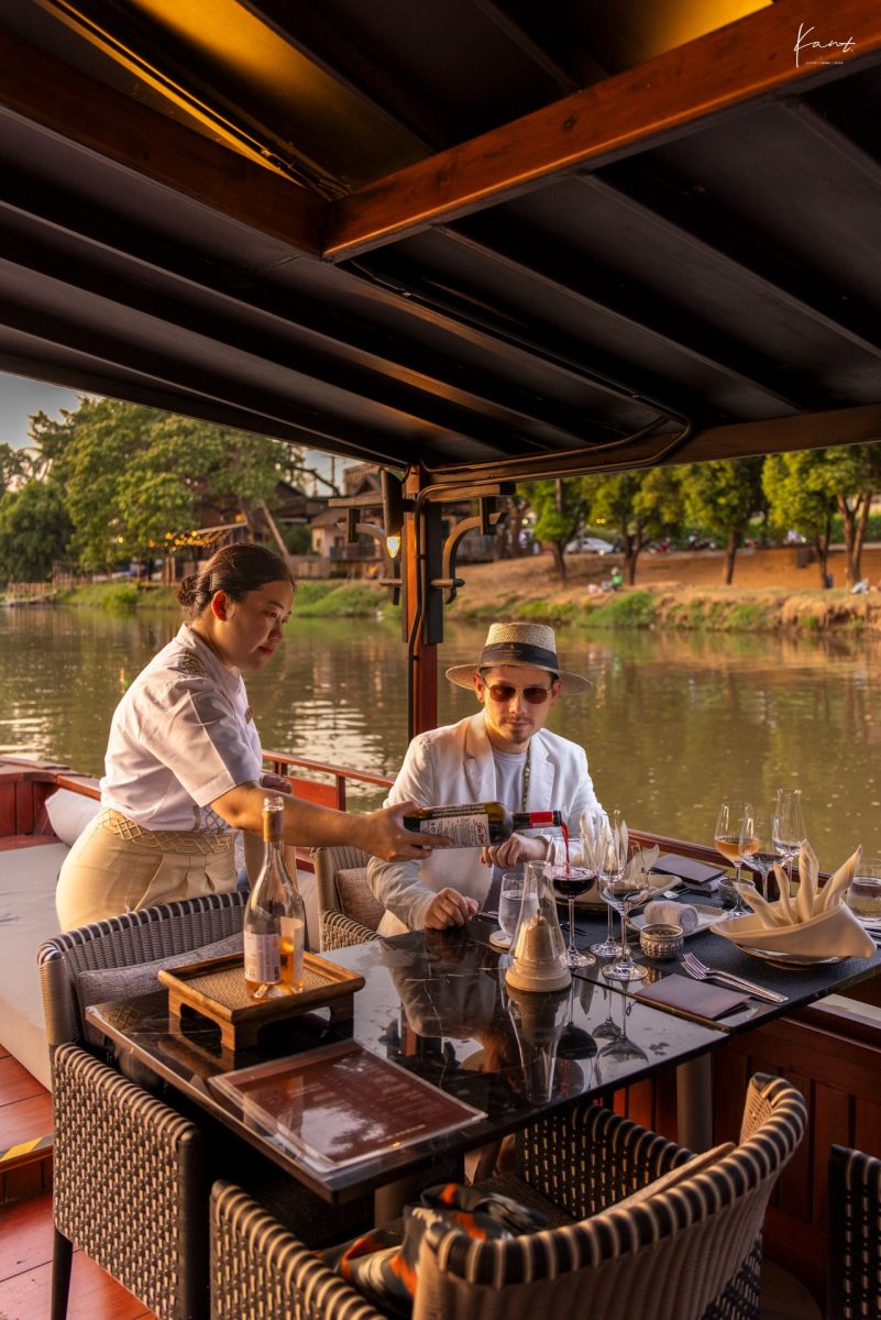 ผู้เข้าพักนั่งบนเรือล่องแม่น้ำปิงพร้อมพนักงานเสิร์ฟ