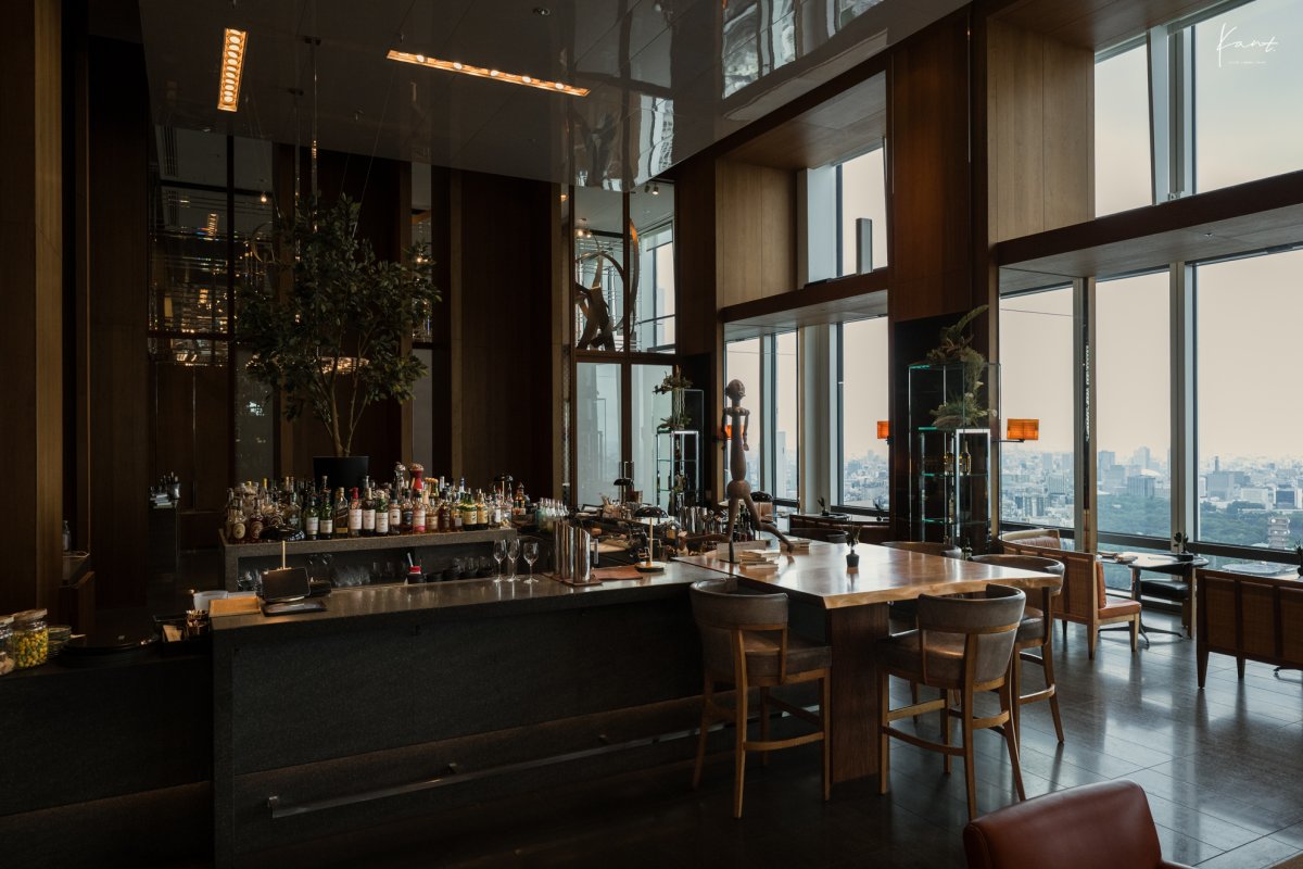 เคาน์เตอร์บาร์ของ The Tavern กับหน้าต่างสูงและวิวโตเกียว