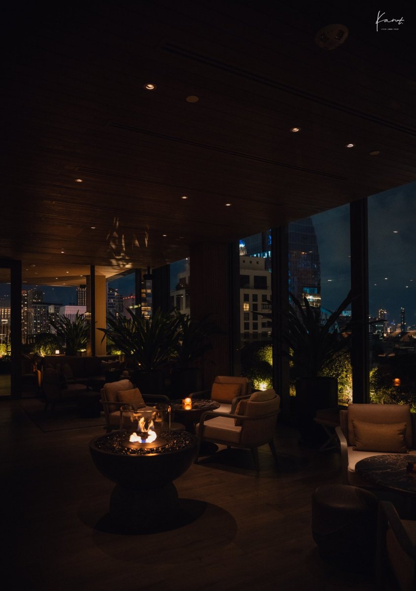 ระเบียงของ Aman Lounge ยามค่ำพร้อมกระถางไฟและวิวเมือง