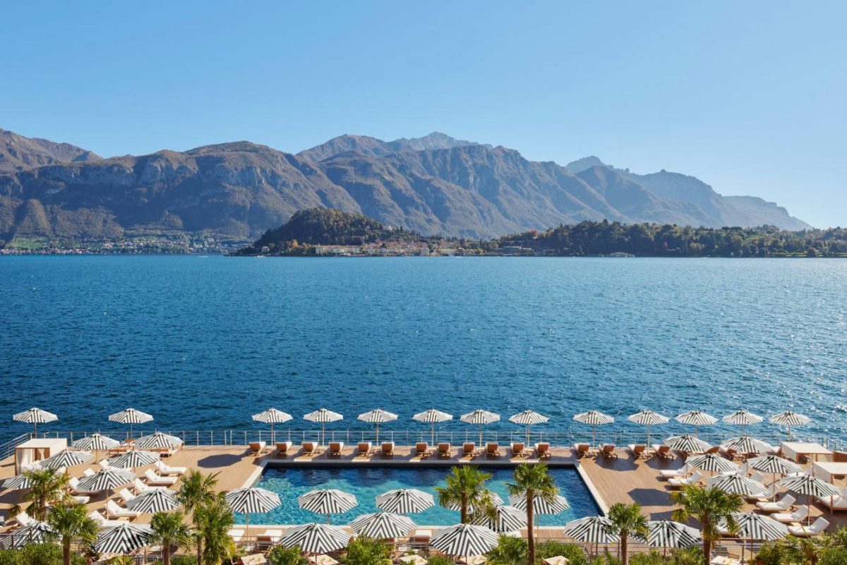 สระลอยน้ำและร่มลายทางของ The Lake Como EDITION มองข้ามทะเลสาบไปยังฝั่ง Bellagio