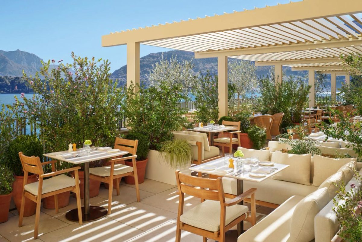 ระเบียงร้าน Renzo ที่ The Lake Como EDITION ใต้ระแนงบังแดด ล้อมด้วยต้นไม้ในกระถางดินเผา