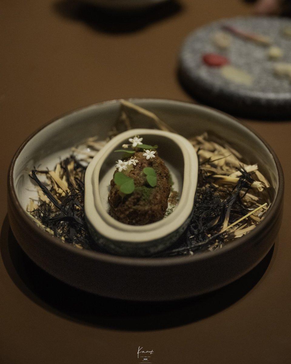 The Hill ชิ้นสีน้ำตาลทรงรีแต่งผงเขียว ใบอ่อน และดอกขาว