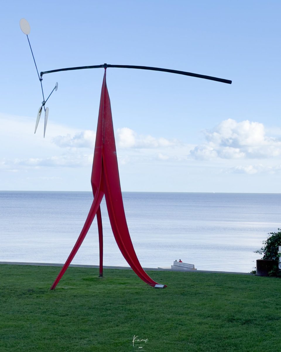 Little Janey-Waney ของ Alexander Calder ขาตั้งสีแดงรับแผ่นโลหะด้านบน มีทะเลเป็นฉากหลัง