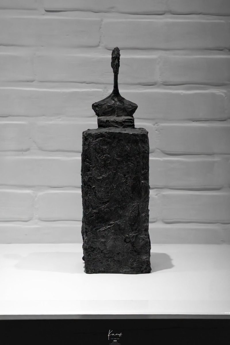 ประติมากรรมรูปคนผอมบางของ Alberto Giacometti บนแท่นในห้องจัดแสดง